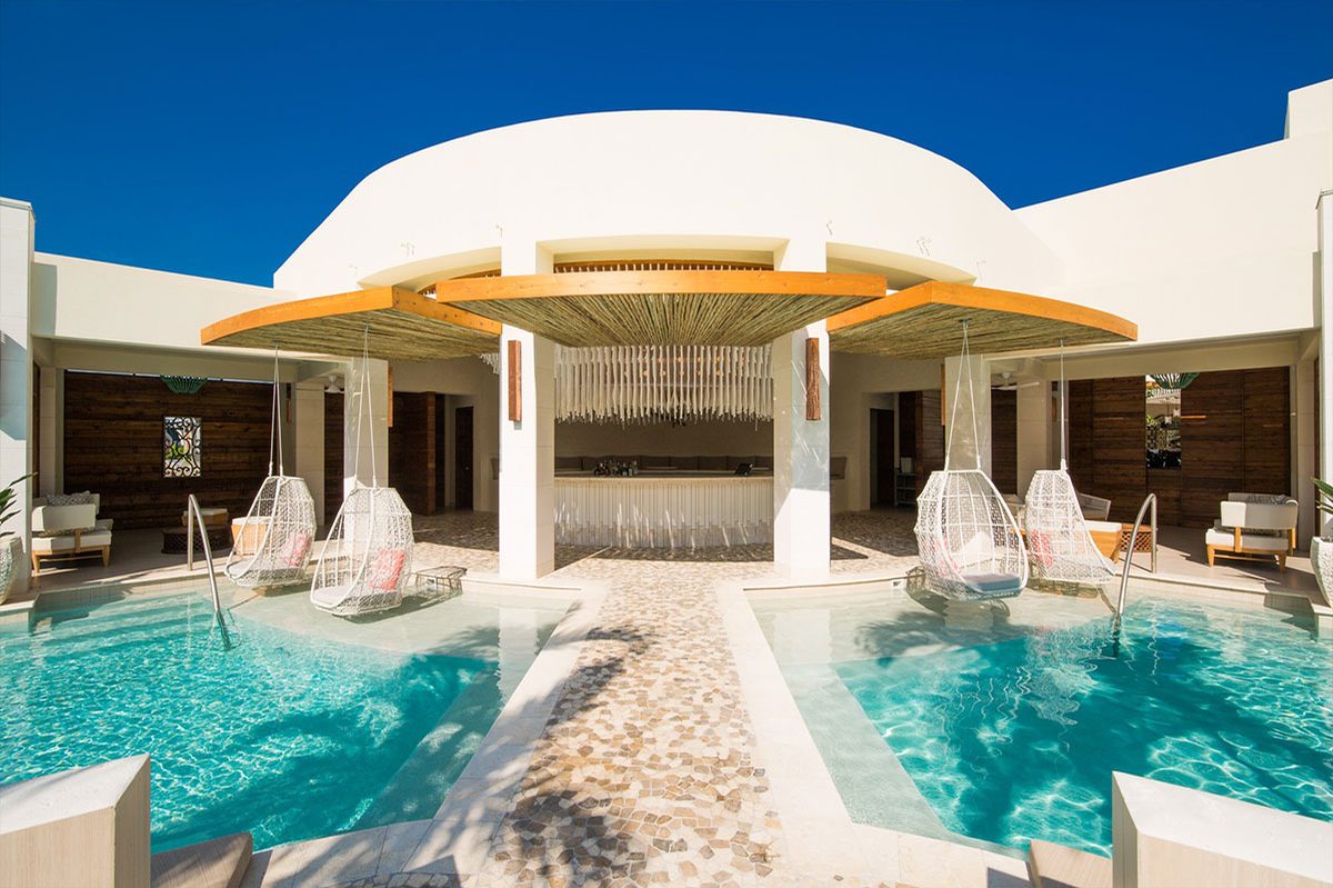 The Colonnade pool bar under its round canopy, with swing chairs over the water