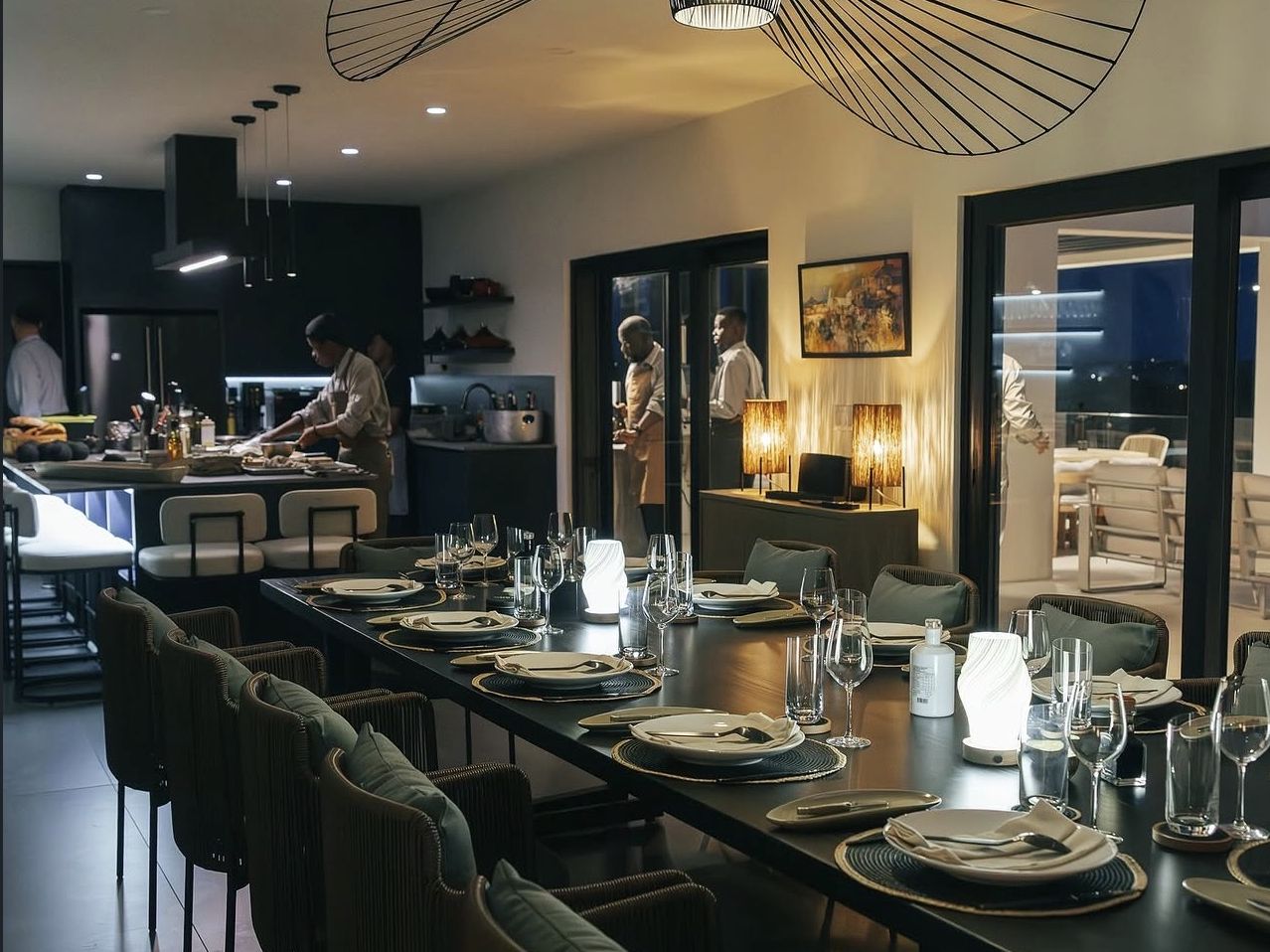The 12-seat chef's table at Ode to Gillian set for dinner, with the open kitchen and chefs at work behind it