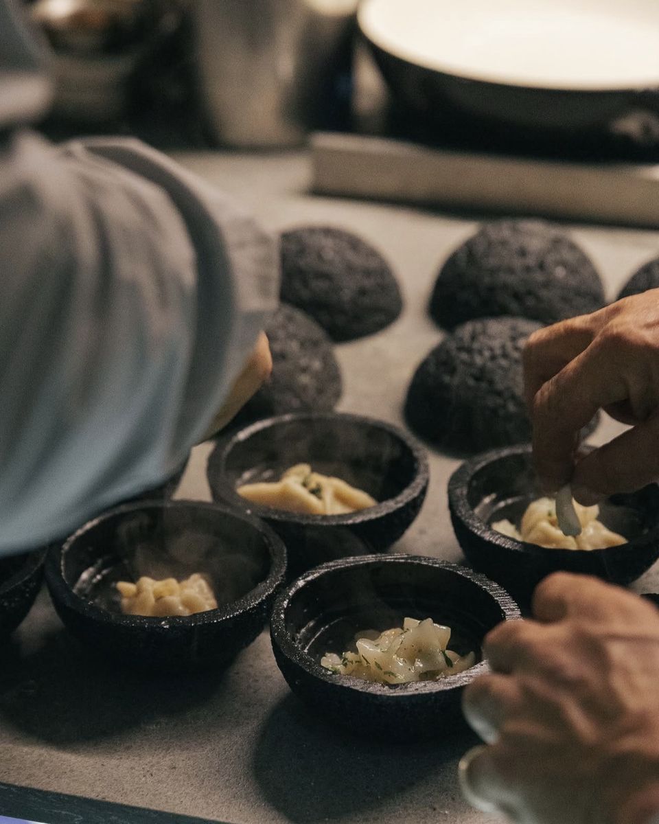A steaming course portioned into black stone bowls at Ode to Gillian