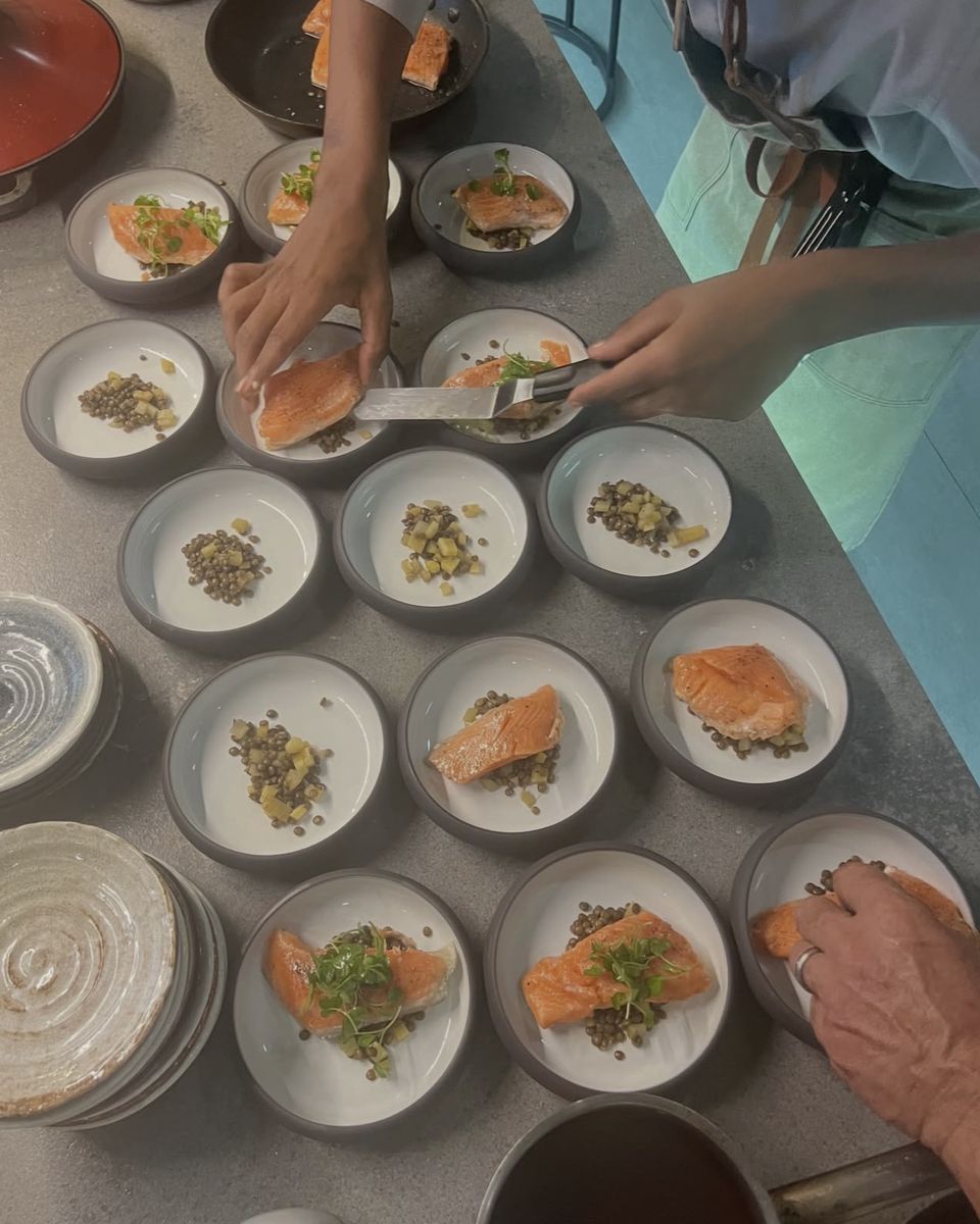 Salmon on lentils being plated for every guest at Ode to Gillian