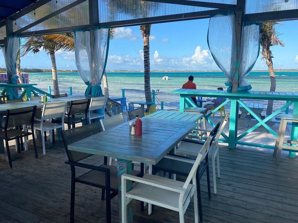 Tables on the covered deck at Omar's Beach Hut, open to the sea breeze and the view