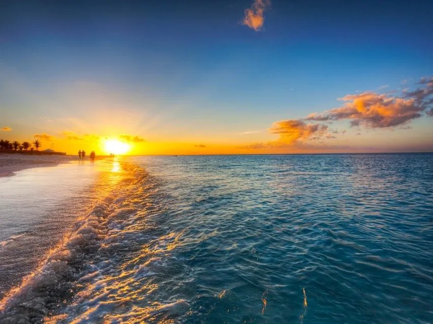 The sun setting over calm water off a Providenciales beach