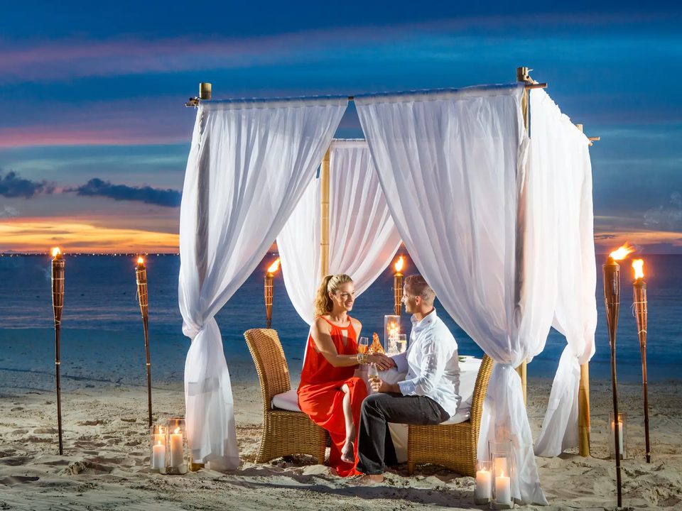 Dinner for two in a curtained cabana on the beach, lit by torches at dusk