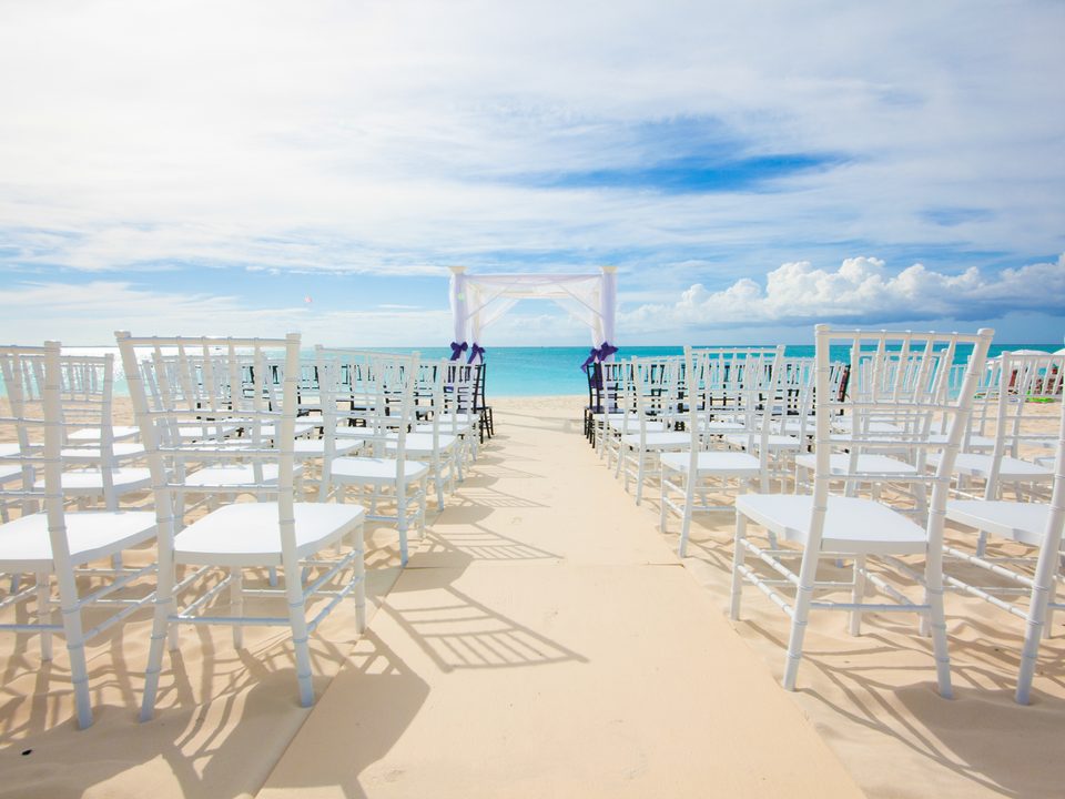 White chairs set for a wedding on the beach