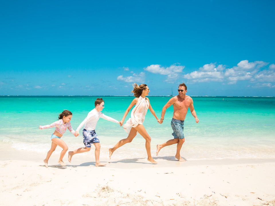A family running into the shallows on Grace Bay Beach