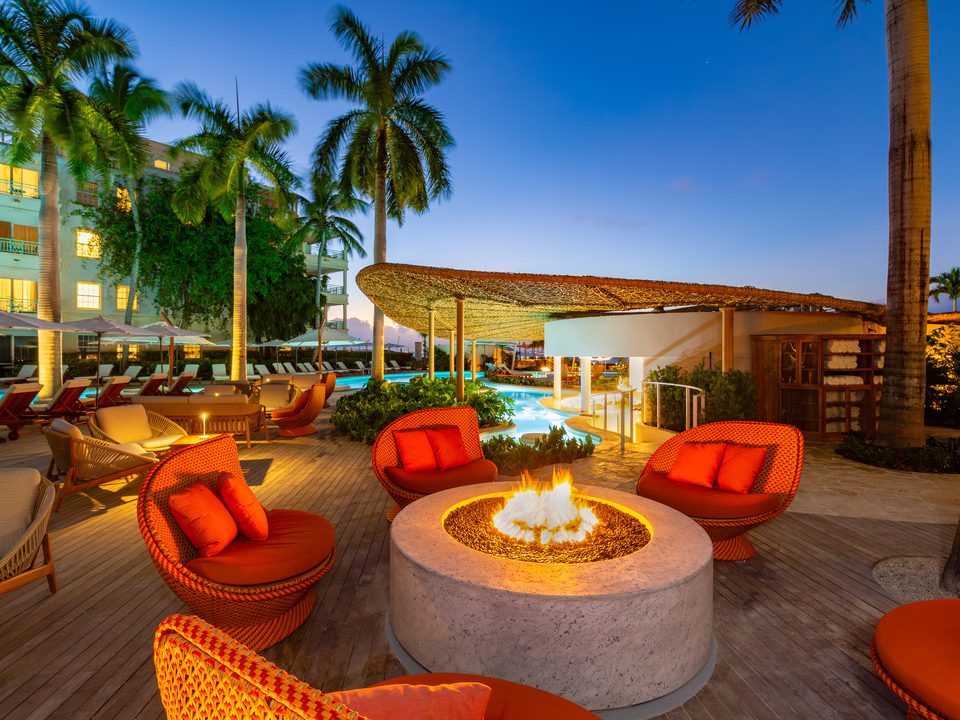 Orange armchairs around a fire pit on the pool deck at dusk
