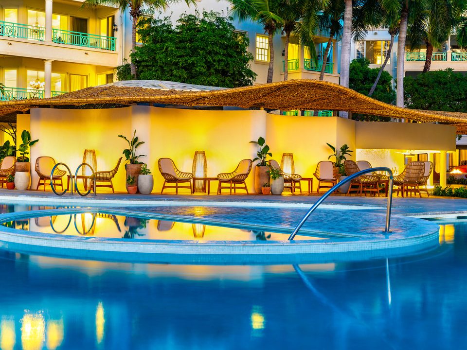 The pool bar lit up at dusk, with the suites behind
