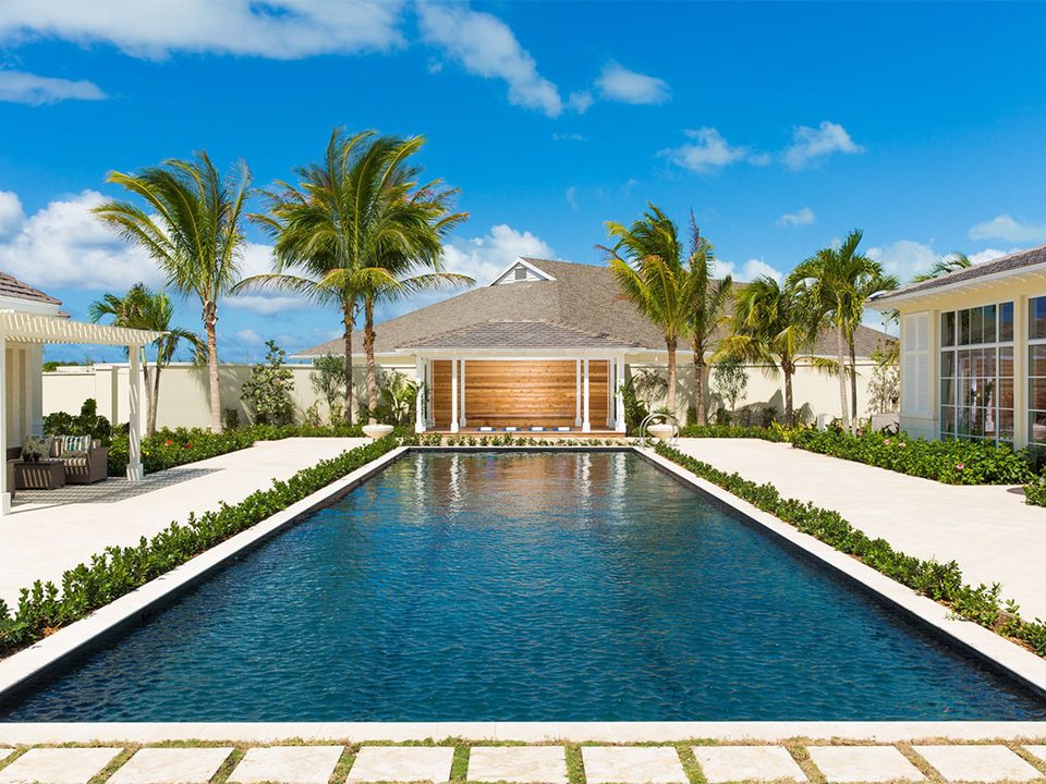 A long pool between lawns and palms