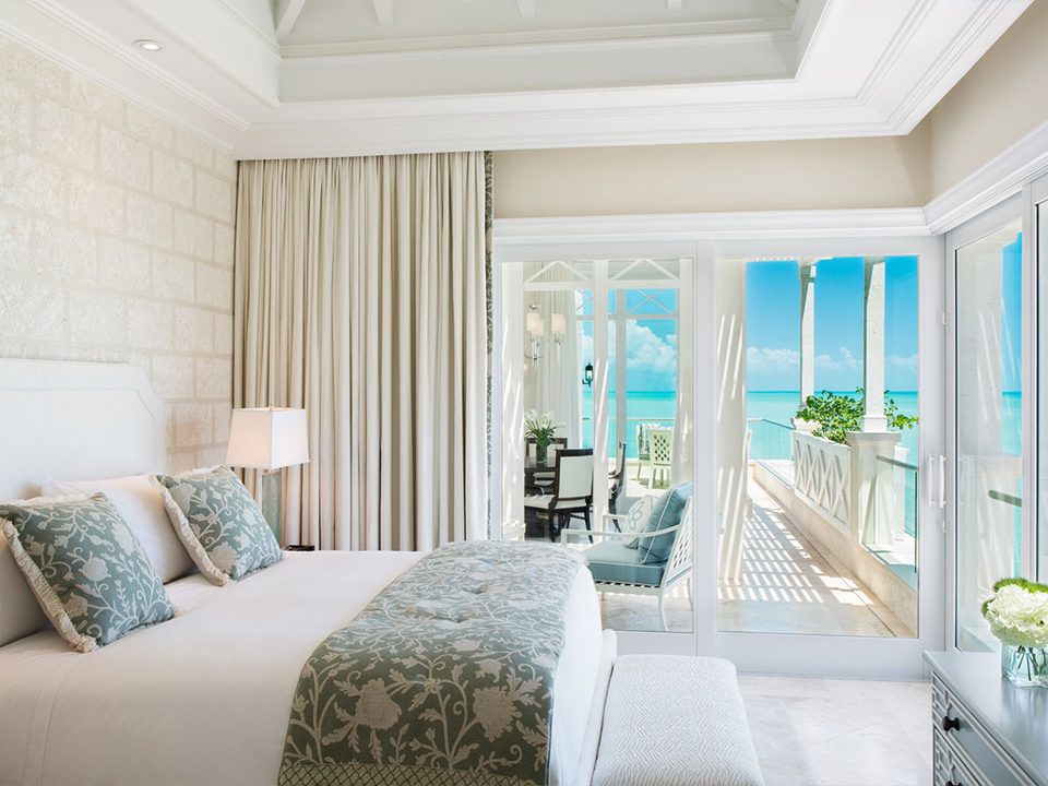 A suite bedroom opening onto a balcony over the sea