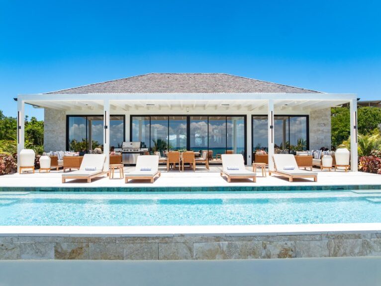 A covered terrace with loungers along the edge of the pool