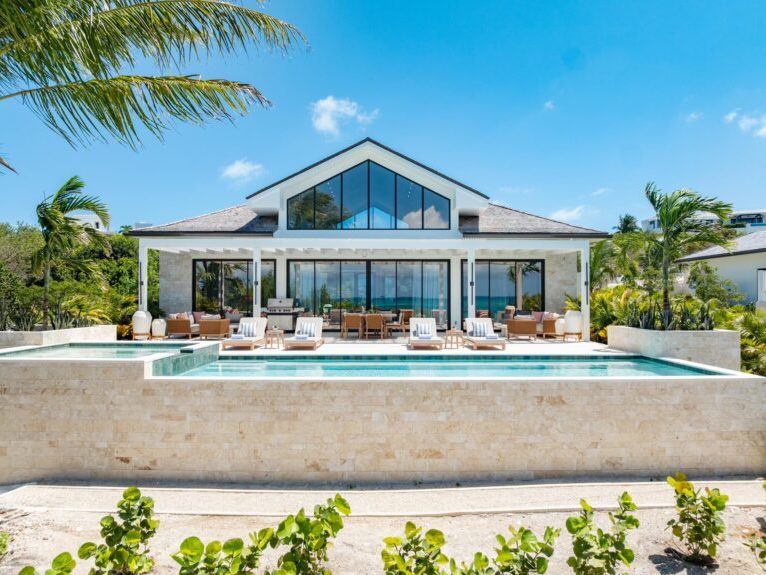 A villa with a glass gable, its terrace and infinity pool