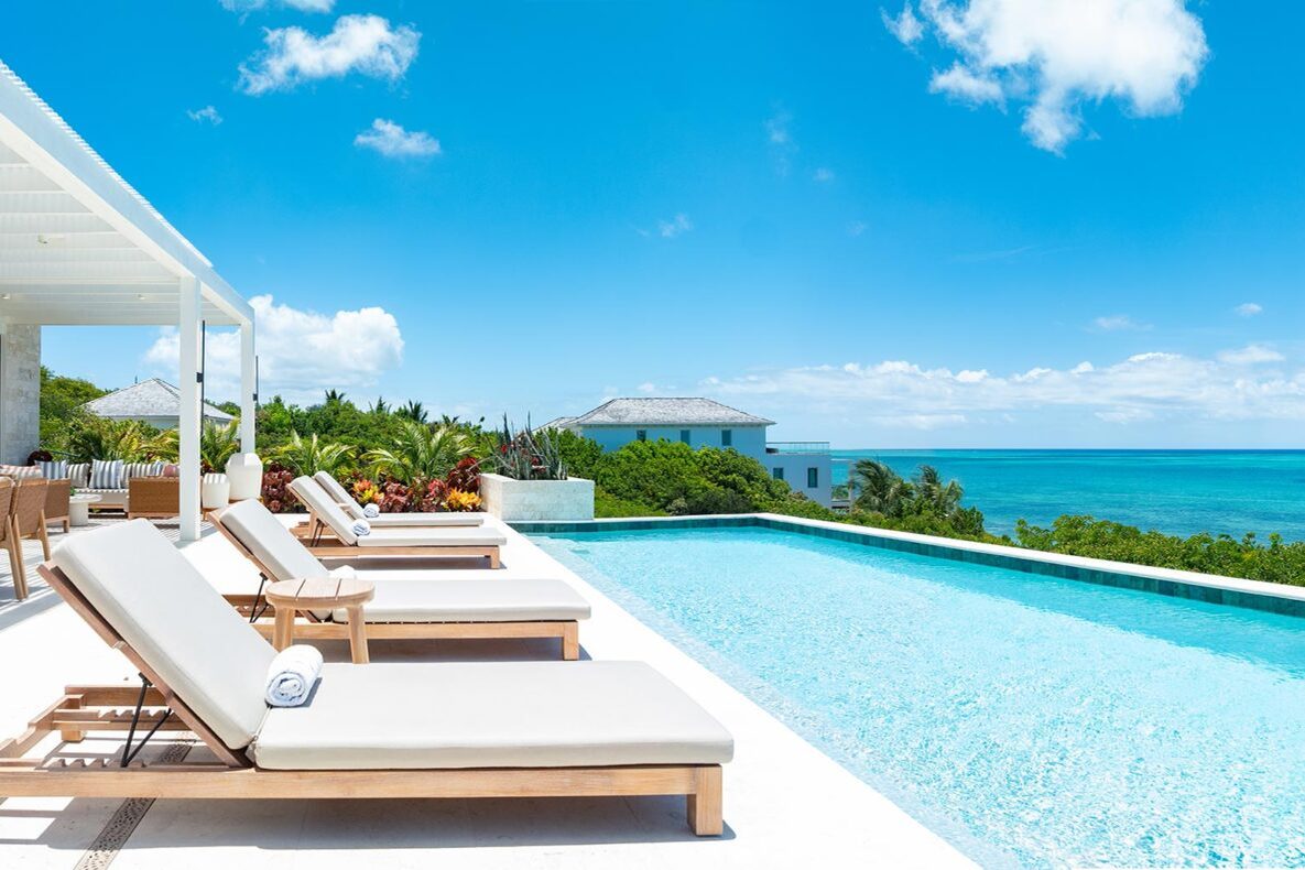 Loungers beside an infinity pool looking out over the turquoise sea
